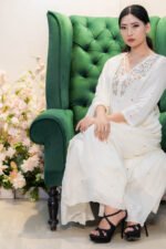 Model wearing the Safed Saaz embroidered modal kurti with matching dupatta, seated gracefully on a sofa, showcasing the relaxed elegance and intricate neckline detailing.