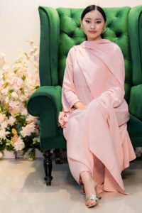 Model seated on tufted armchair wearing Aangan Aura kurti with lace-trimmed dupatta