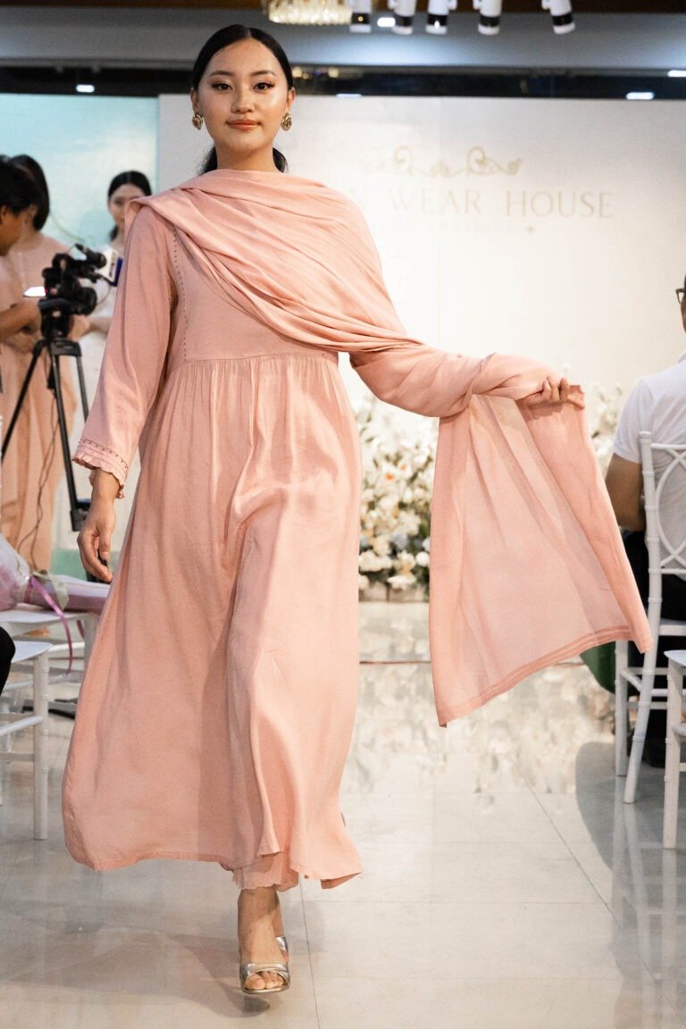 Model walking down runway in Aangan Aura ensemble during fashion show