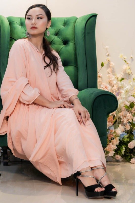 Woman wearing embroidered kurti set seated on a sofa with elegant pose