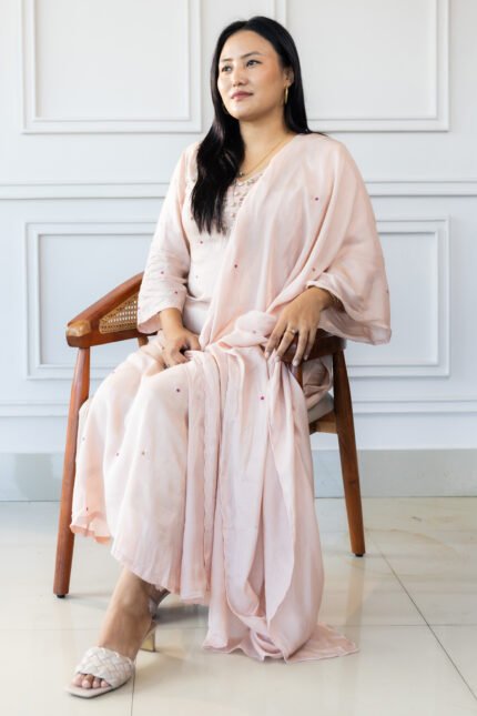 Woman seated on a chair wearing Sakura pastel embroidered kurti with dupatta โ elegant ethnic wear look