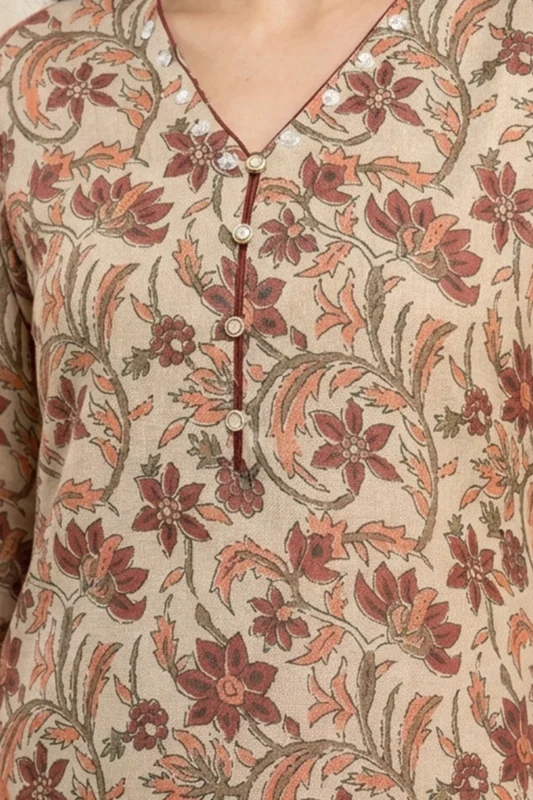 Close‑up of a beige kurta with red, orange, and green floral patterns, maroon piping on V‑neckline, decorative buttons, and embroidered accents.