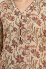 Close‑up of a beige kurta with red, orange, and green floral patterns, maroon piping on V‑neckline, decorative buttons, and embroidered accents.