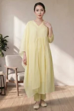 Full studio shot of a model wearing the Canvas Kurti V Neck yellow set, featuring a gathered waist kurta, straight-fit trousers, and a matching lace-bordered dupatta.