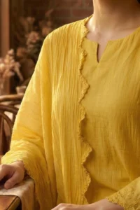 Close-up of the delicate scalloped lace and tonal embroidery on the neckline of the mustard Saaz kurti.