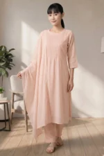 Full-length photo of a woman wearing the Ora Ethnic light pink kurta and pant set, with the chiffon dupatta draped gracefully over one arm, standing in a brightly lit room.