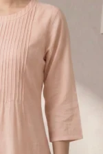 Close-up of Ora Ethnic kurta neckline, showing light pink cotton-linen fabric with multiple narrow vertical pin-tucks on the bodice and a simple round neck.