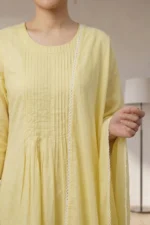 Detailed view of the Canvas kurti’s front bodice featuring vertical pintuck pleats and a round neckline. A matching yellow dupatta with delicate white scalloped lace edging is draped over the shoulder.