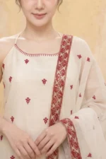 A close-up view of the StyleMélange maroon kurta’s bodice. The natural-toned fabric features a clean halter neckline accented with a thin maroon embroidered trim. Small, evenly spaced maroon floral motifs decorate the chest, while a sheer dupatta with a dense maroon floral border is draped over the shoulder.