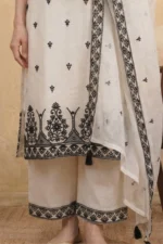 A detailed shot of the lower portion of the StyleMélange ensemble. The natural beige kurta features an intricate, oversized black scalloped embroidery pattern at the hem, detailed with geometric motifs and tiny mirrors. The wide-leg palazzos show a coordinating black embroidered border at the ankles for a sophisticated, high-contrast finish.