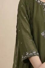 A close-up shot of the three-quarter sleeve on the red Gulmohar kurti, highlighting a wide white embroidered border with floral and geometric patterns against the rich red fabric.