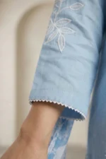Close-up of white floral embroidery on the sleeve of a light blue linen Edge kurti.