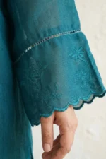 Close-up of intricate white floral embroidery on the sleeve of a teal linen Vogue kurti.