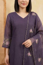 A detailed close-up of the kurti's bodice, showcasing structured vertical pintuck pleats and handcrafted decorative tassels hanging from the neckline. Subtle floral threadwork is visible on the shoulders, highlighting the premium craftsmanship.