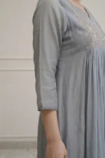 A focused shot of the three-quarter length sleeve of the teal Majuli Muse kurti. It features a wide floral embroidered cuff and a delicate scalloped edge, highlighting the premium fabric texture.