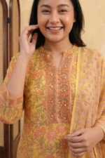 A close-up of the Mehak yellow kurta’s bodice. It features a Mandarin collar with a V-slit neckline. The central bib panel is decorated with a peach-toned floral print and accented with delicate hand-stitched sequins and small buttons. The signature square weave of the Kota Doria fabric is visible in the texture.