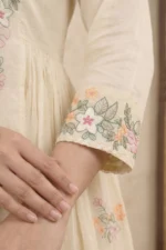 A focused shot of the three-quarter length sleeve, featuring a wide embroidered cuff with detailed floral motifs and a scalloped lace edge. The fabric has a premium, lightweight texture that showcases the fine thread-work.