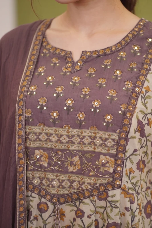Close-up of the Amara kurti's bodice showing the mauve fabric with delicate gold sequin floral embroidery and a contrasting printed border along the waistline.