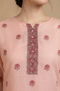 Close-up of the Blush Buti Kurta Set featuring a round neckline with a decorative embroidered placket adorned with intricate floral threadwork and sequin mirror accents on soft blush pink textured check cotton fabric with scattered pink buti print motifs