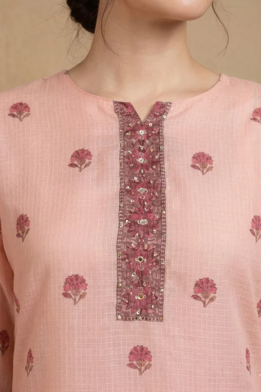 Close-up of the Blush Buti Kurta Set featuring a round neckline with a decorative embroidered placket adorned with intricate floral threadwork and sequin mirror accents on soft blush pink textured check cotton fabric with scattered pink buti print motifs