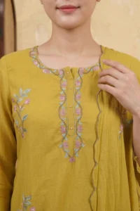 Close-up of the Mustard Vine Kurta Set featuring a round neckline with intricate pink and sage green vine and floral threadwork embroidery with delicate pearl button accents