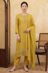 A woman wearing the Mustard Vine Kurta Set comprising a straight-cut floral embroidered kurta with vine motifs, matching straight-leg pants, and a flowing dupatta, styled with gold juttis