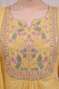 Yellow Garden Kurta Set – Detailed Floral Embroidered Yoke with Mirror Work Alt text: Close-up of the Yellow Garden Kurta Set featuring an elaborate square yoke with dense pink, sage green and gold floral and leaf threadwork embroidery in a garden motif pattern, framed by a decorative mirror work border on soft yellow cotton fabric