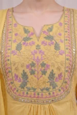 Yellow Garden Kurta Set – Detailed Floral Embroidered Yoke with Mirror Work Alt text: Close-up of the Yellow Garden Kurta Set featuring an elaborate square yoke with dense pink, sage green and gold floral and leaf threadwork embroidery in a garden motif pattern, framed by a decorative mirror work border on soft yellow cotton fabric