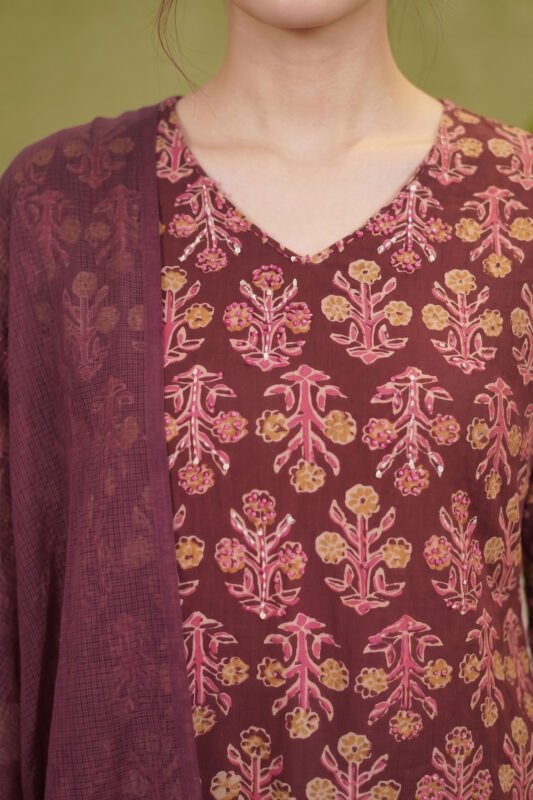 Detailed view of the three-quarter sleeves and side panel of a deep wine ethnic suit showcasing traditional Indian paisley and striped border prints.