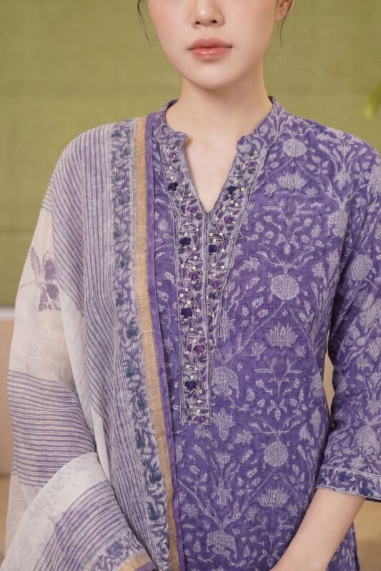 Close-up of the Indigo Petal Set's neckline showing intricate floral embroidery, purple beadwork accents, and a subtle V-slit on a lavender printed fabric.