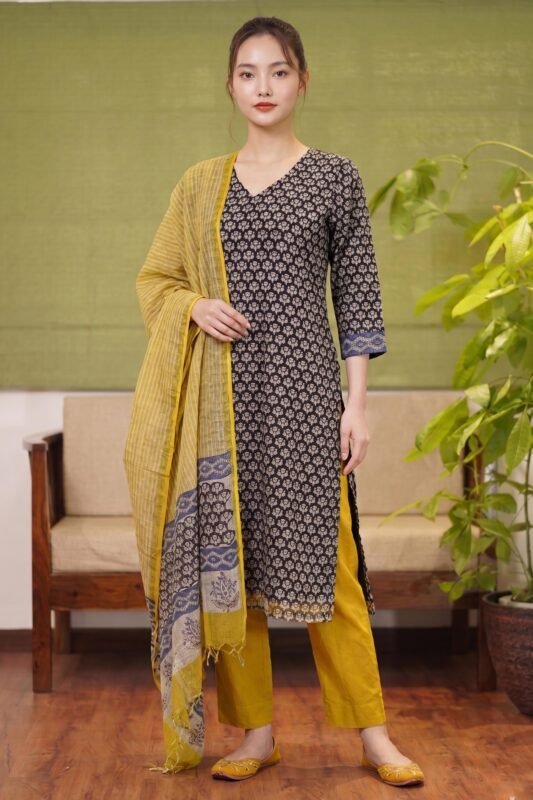 Full-length view of the Midnight Buta Suit featuring a black floral printed kurta with V-neckline, paired with vibrant mustard yellow trousers and a striped dupatta.