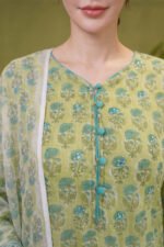 Close-up of the pistachio green kurta neckline featuring teal fabric-wrapped buttons, intricate floral buta prints, and subtle mirror work embroidery.