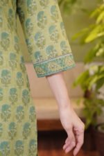 Detailed shot of the three-quarter sleeves on the pistachio green ethnic suit, showing the contrast leaf-patterned border and textured cotton fabric.