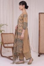 Side profile view of a model wearing the beige Oasis Print Kurti set, highlighting the straight-cut silhouette, side slit alignment, and matching geometric print trousers. The patterned dupatta falls elegantly against a minimal studio background with beige curtains and wooden accents.