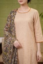 Close-up of the Sand Dot Kurti showcasing the round neckline with contrasting scalloped edging, precise yoke alignment, scattered embroidered dot motifs on the bodice, and a dark floral dupatta draped over the shoulder.