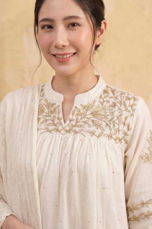 Close-up of the Zari Kurti yoke featuring a mandarin collar with a V-split, detailed gold floral embroidery, and technical pleating for a premium finish.