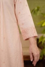 Sleeve and embroidery detail of a light cream Chanderi kurti, featuring scattered floral motifs and a detailed floral hem border.
